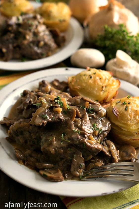 Slow Cooker Swiss Steak - Fork-tender beef cooked in the crockpot with a rich delicious onion and mushroom gravy. Pure comfort food!