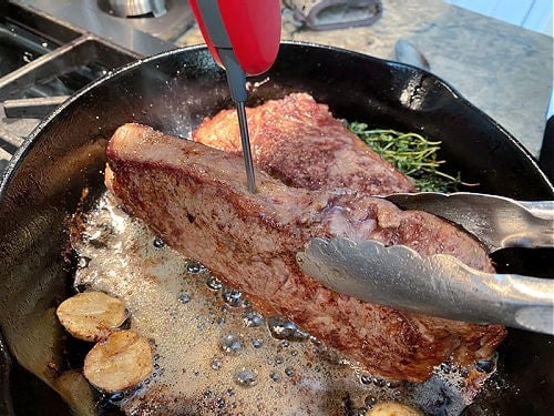 Inserting probe thermometer into sirloin steak